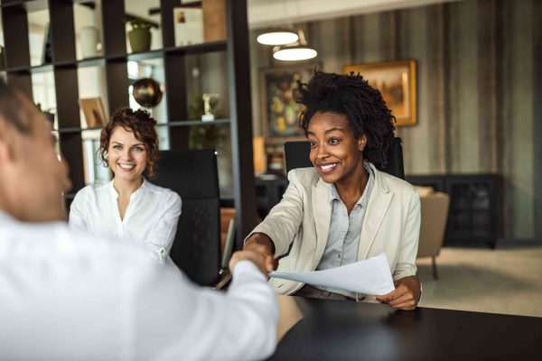 Business woman doing hand shake with another colleague.