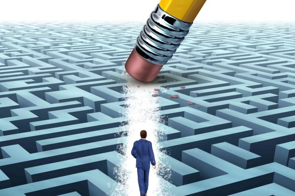 Leadership Solutions with a businessman walking through a complicated maze opened up by a pencil eraser as a business concept of innovative thinking for financial success.